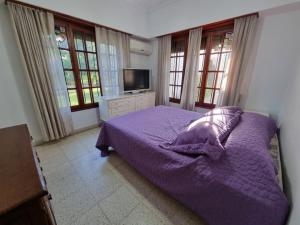 a bedroom with a purple bed and a tv at Espectacular casa quinta al río! in Sauce Viejo