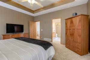 a bedroom with a large bed and a flat screen tv at Spacious Pool House with tons of amenities! in Omaha