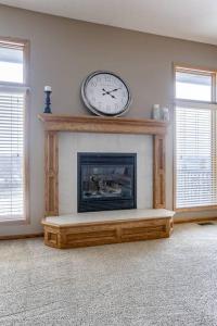 a living room with a fireplace with a clock on the wall at Spacious Pool House with tons of amenities! in Omaha