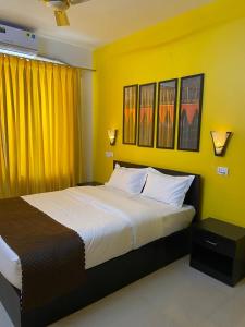 1 dormitorio con 1 cama grande y paredes amarillas en Serenity Casa, en Talaulim