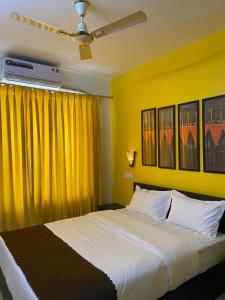 1 dormitorio con 1 cama blanca grande con cortinas amarillas en Serenity Casa, en Talaulim