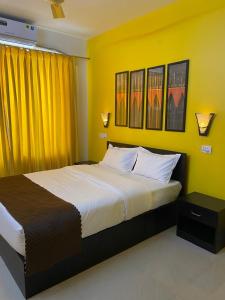 1 dormitorio con 1 cama grande y paredes amarillas en Serenity Casa, en Talaulim