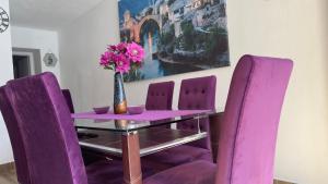 uma mesa roxa com cadeiras roxas e um vaso com flores em Villa Zigana em Mostar