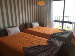 ポルティマンにあるApartamento Cruzeiro Praia da Rochaのベッド2台と窓が備わるホテルルームです。