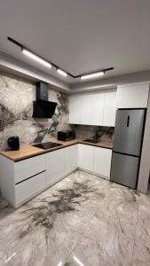 cocina con armarios blancos y nevera en Центр&Новобудова& ЖК Театральний&Простора студія& en Rivne