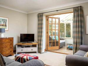 a living room with a television and a sliding glass door at Hope Cottage in Moreton in Marsh