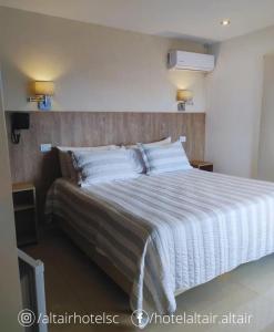 1 dormitorio con 1 cama grande y cabecero de madera en Altair Hotel en San Clemente del Tuyú