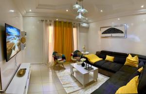 sala de estar con sofá negro y almohadas amarillas en Bel appartement meublé, en Dakar