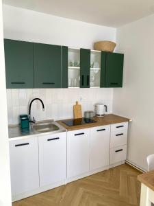 a white kitchen with green cabinets and a sink at Apartament Zielone Serce Miasta in Mrągowo