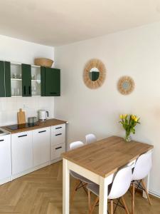 a kitchen with a wooden table and white cabinets at Apartament Zielone Serce Miasta in Mrągowo