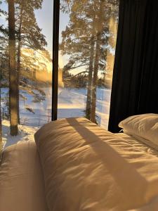 ein Bett vor einem Fenster mit Schnee in der Unterkunft Spegle Hyllandsfoss in Åmot