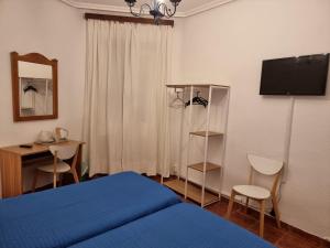 Un dormitorio con una cama, un escritorio y un televisor. en Casa de Huéspedes Cuenca, en Madrid