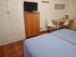 1 dormitorio con 1 cama, TV y mesa en Casa de Huéspedes Cuenca, en Madrid 37 fotos más