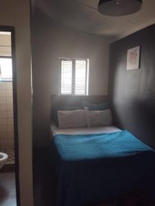 a small bedroom with a bed with a blue blanket at E-JOFF Lodge in Johannesburg