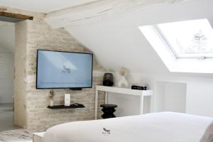 1 dormitorio con 1 cama y TV en la pared en Plume Suites, en Fleurey-sur-Ouche