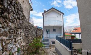 - un bâtiment blanc avec des escaliers à côté d'un mur en pierre dans l'établissement Apartment Ado, à Mostar