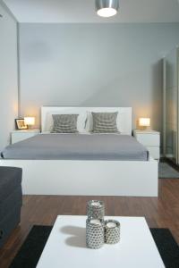 a white bedroom with a large bed and a table at Charm Apartments And Rooms in Trogir