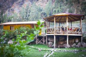 ein gelbes Haus mit einer Terrasse auf einem Feld in der Unterkunft Eco Lodge Cabañas con Piscina in Urubamba