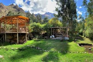 une cour verdoyante avec un bâtiment, des arbres et des montagnes dans l'établissement Eco Lodge Cabañas con Piscina, à Urubamba