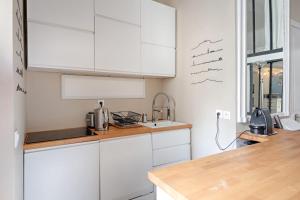 a kitchen with white cabinets and a sink at Loft studio in the heart of Paris - Welkeys in Paris