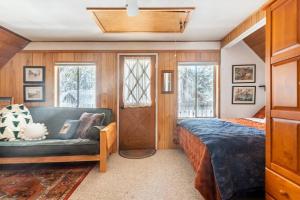 a bedroom with a couch and a bed and windows at Quaint Cabin in Serene Lakes - Close to Skiing! in Soda Springs