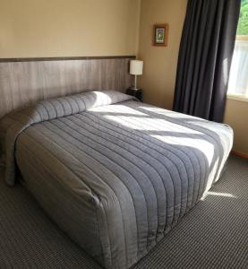 a bedroom with a large bed with a blue blanket at Smylies Accommodation in Springfield