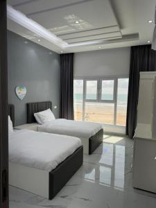 Sea View Chalet Al Ashkharah في الشرقية: سريرين في غرفة نوم مطلة على الشاطئ