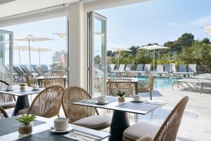 a restaurant with tables and chairs and a pool at Exe Portals Nous in Portals Nous
