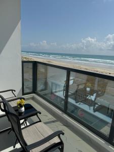 Sea View Chalet Al Ashkharah في الشرقية: شرفة مع طاولة وكراسي والشاطئ