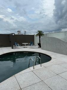 a swimming pool with two chairs and a table at Flat Saint Paul Retro in Brasilia