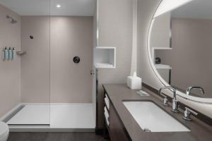 La salle de bains est pourvue d'une douche, d'un lavabo et d'un miroir. dans l'établissement Courtyard by Marriott Orem University Place, à Orem