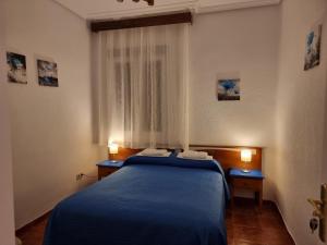 a bedroom with a blue bed and two night stands at Casa de Huéspedes Cuenca in Madrid