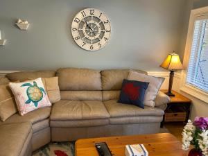 a living room with a couch and a clock on the wall at Unique 3BR, 1 of 5 Condos w/Huge Poolside Patio, Steps to Beach & Pier, Gated in Tybee Island