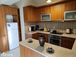 a kitchen with wooden cabinets and a white refrigerator at Spacious 2bedroom apartment in Chalkida