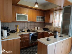 a kitchen with wooden cabinets and a stove top oven at Spacious 2bedroom apartment in Chalkida