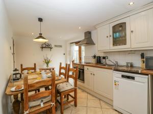 a kitchen with a table and chairs and a kitchen with white cabinets at Beekeeper's Cottage in Leominster
