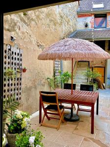 een houten tafel met een grote parasol en een stoel bij Le nid d’Isa in Hautvillers