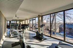 a gym with treadmills and ellipticals in a room with windows at Lakefront Condo with Resort Amenities in Osage Beach in Osage Beach