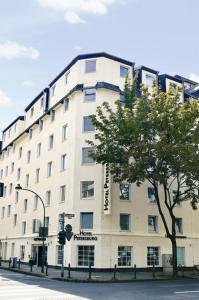 ein großes weißes Gebäude mit einem Baum davor in der Unterkunft Apartments Hotel Petersburg in Düsseldorf