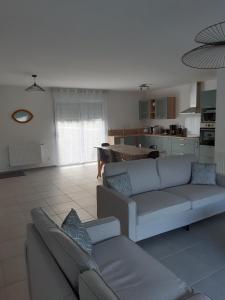 a living room with two couches and a kitchen at Gîte neuf in Dampierre-en-Burly