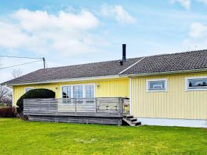 uma casa amarela com um grande alpendre num quintal em Holiday home STILLINGSÖN IV em Stillingsön