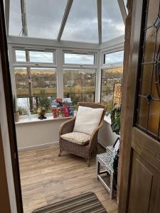 a conservatory with a chair in a room with windows at Sealladh Sona in Inverness