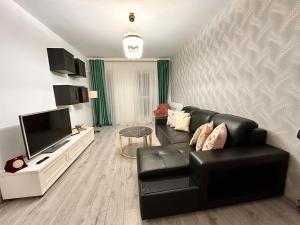 a living room with a black leather couch and a television at Galaxy Residence Apartament in Popeşti-Leordeni