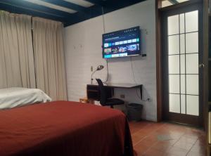 - une chambre avec un bureau et une télévision murale dans l'établissement Casa del Aguacate Cumbaya - Tumbaco, à Cumbayá