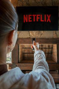 a woman holding a cell phone in front of a netflix sign at Posada Bonarda in San Rafael