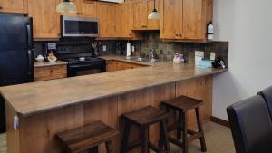una cocina con armarios de madera y una barra con taburetes en Settlers Crossing #41 by Bear Country, en Sun Peaks