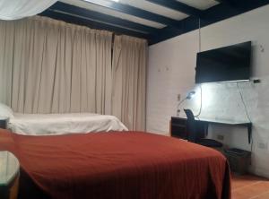 - une chambre avec un lit rouge et une télévision dans l'établissement Casa del Aguacate Cumbaya - Tumbaco, à Cumbayá