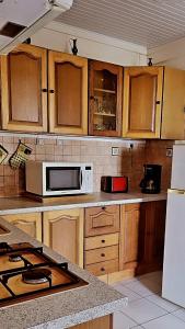 Una cocina con gabinetes de madera y microondas. en Le Bougainvillier, en Le Vauclin 6 fotos más