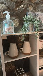 un estante con dos tazas y una botella de detergente en La Grotta di Leonardo a Vinci, en Quarrata