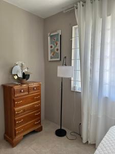 a bedroom with a dresser and a lamp next to a window at The Shelton - Sinclair in Montego Bay